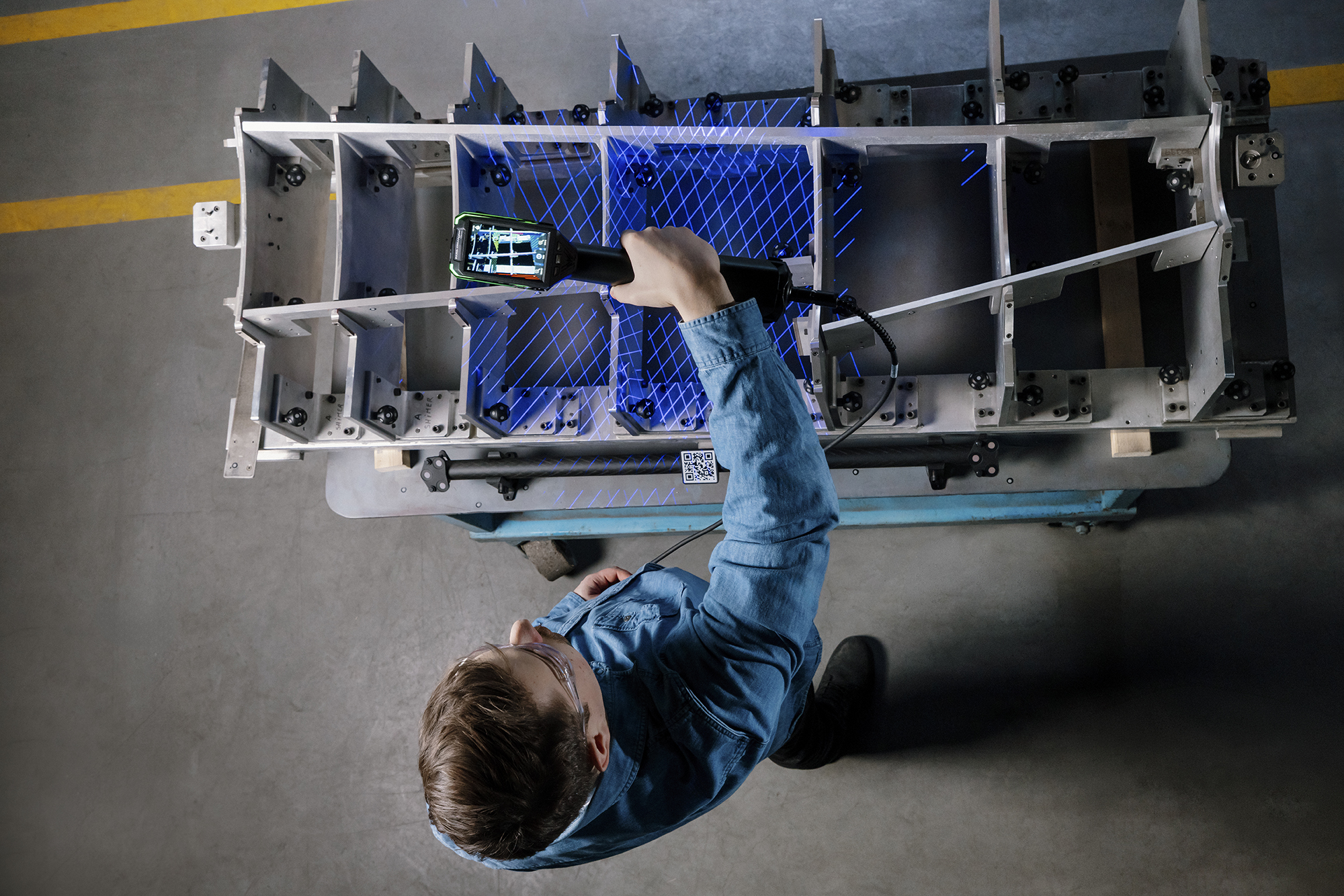 Un metrólogo escaneando un accesorio de inspección aeroespacial con el escáner HandySCAN MAX EVO, con el escaneado en vivo visible en la pantalla integrada.