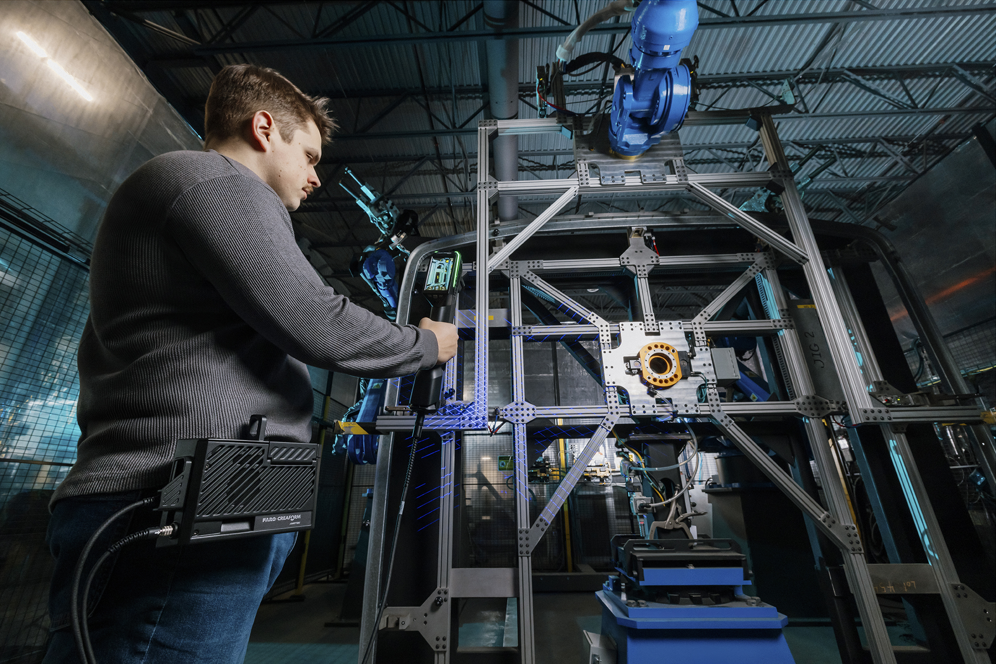 Un hombre realizando una inspección de un bastidor escaneando un accesorio de inspección de gran tamaño con el escáner HandySCAN 3D Serie MAX y el Kit móvil inalámbrico.