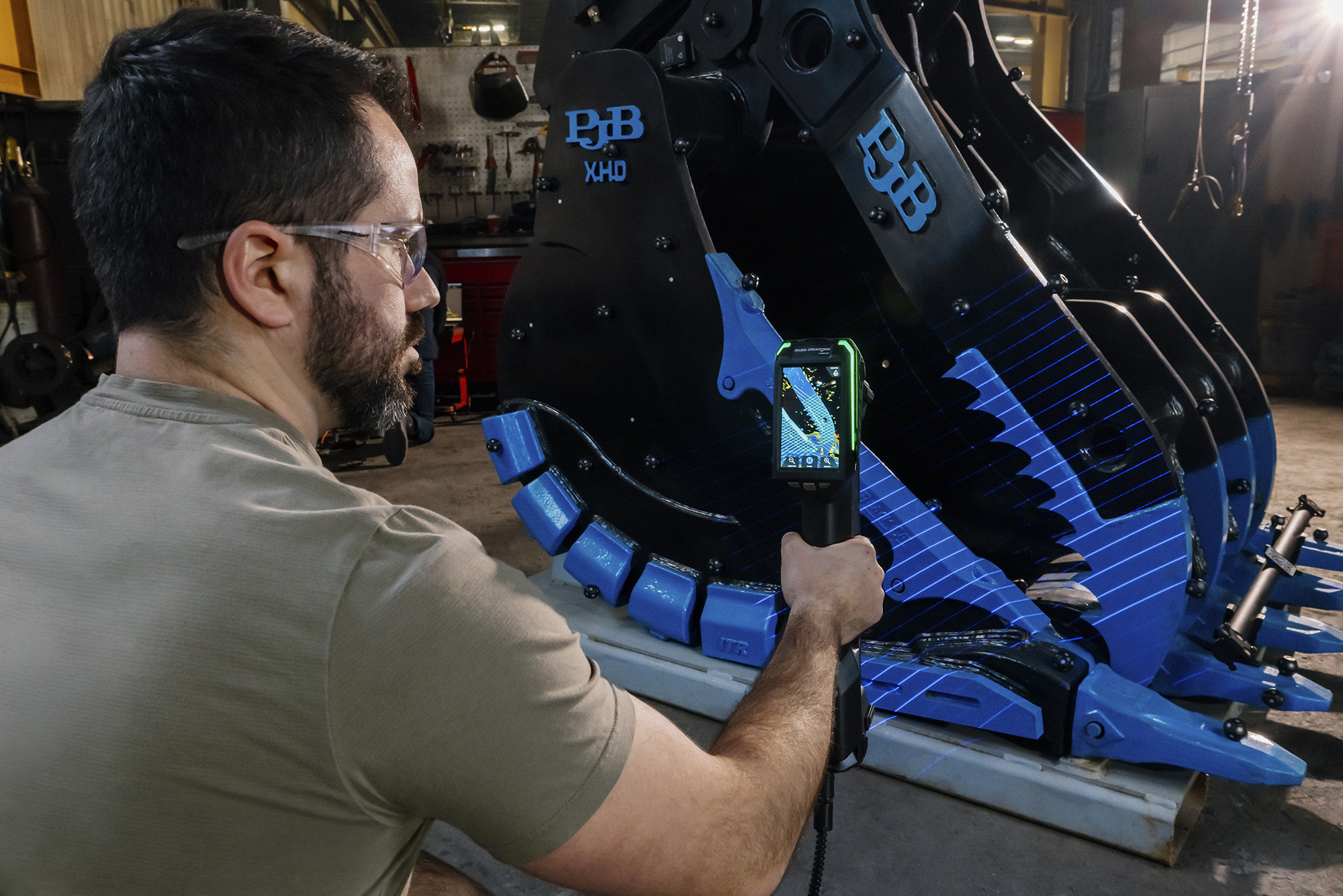Un usuario escaneando un componente tipo garra con el escáner HandySCAN MAX EVO, con el escaneado en vivo mostrado en la pantalla integrada del escáner.