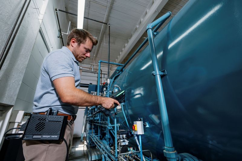 Um metrologista realizando medições em 3D de uma autoclave usando um escâner 3D sem fio alimentado por bateria