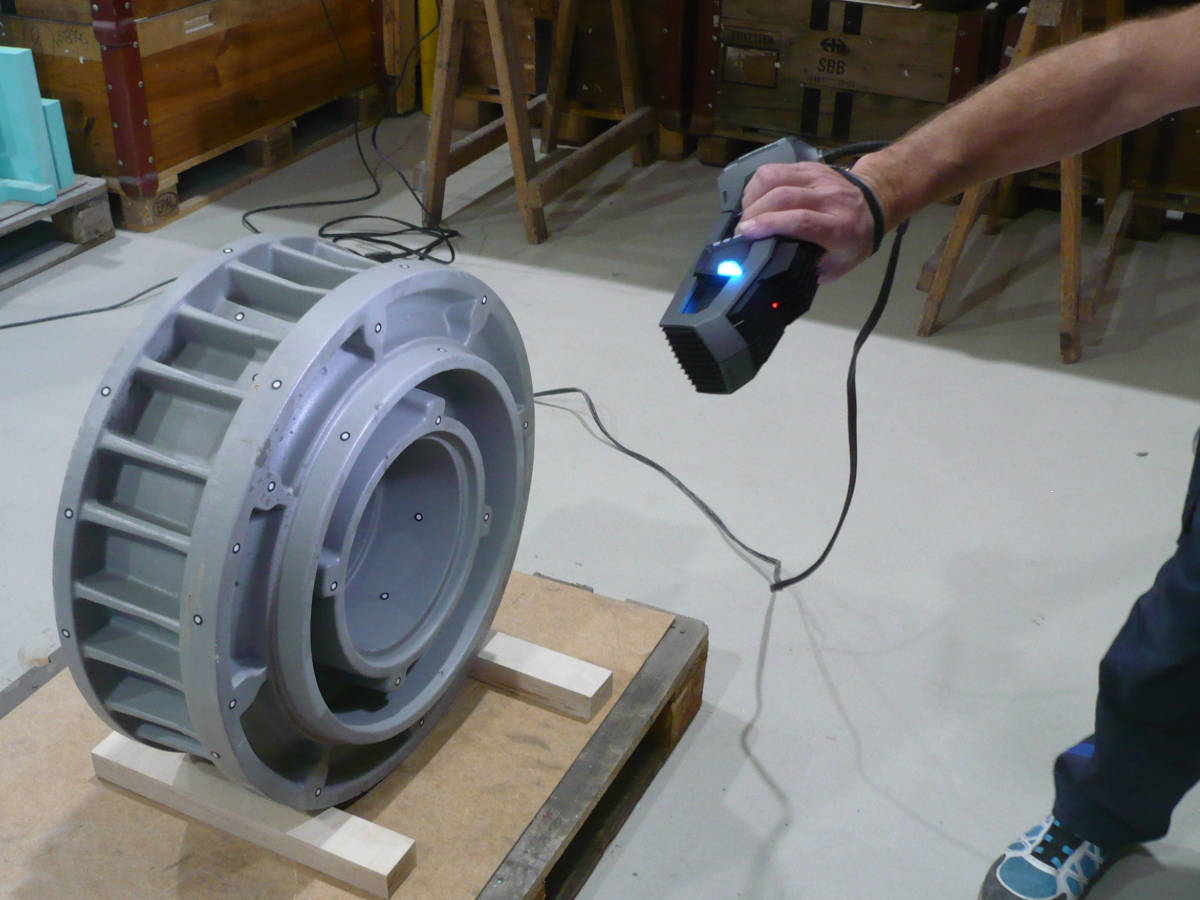 Hombre utilizando un Go!SCAN 3D para medir una carcasa de cámara de aceite en un palé