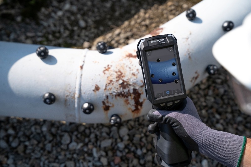 Scanner 3D manuale HandySCAN EVO|Elite che acquisisce dati e visualizza la scansione sul suo schermo integrato durante l’ispezione di un tubo arrugginito dell’olio con l’applicazione di diversi marcatori.