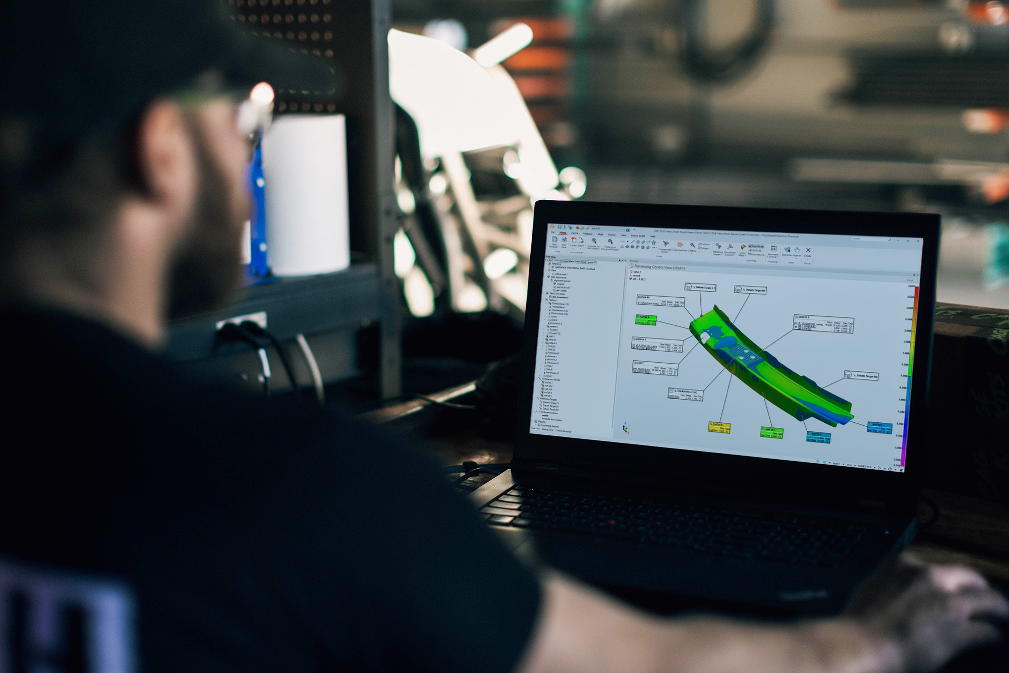 一名男子在车间里通过电脑上的 PolyWorks 查看航空零部件及其色图。