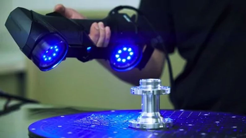 A hand holding the scanner ready to be used to scan a part