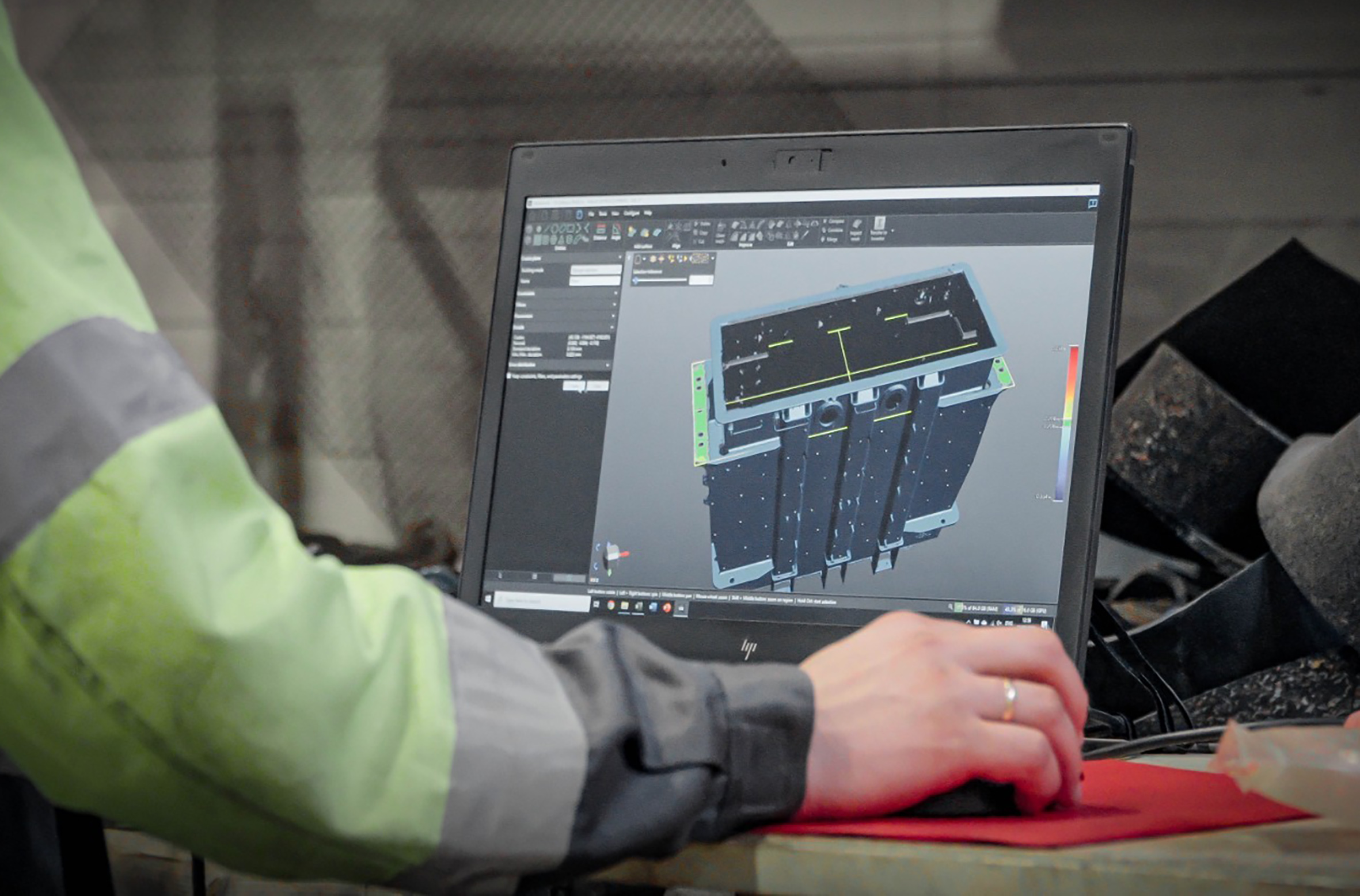 Employee in the shop, working on a laptop displaying the blue 3D rendering of the transformer tank