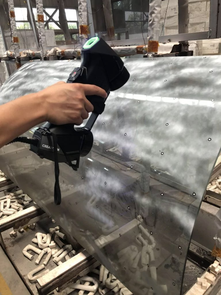 Close-up of someone using the HandySCAN 3D|BLACK Series scanner to scan a curved glass part directly in the shop