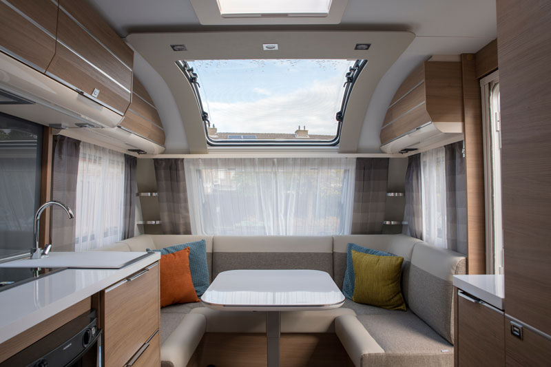 Interior of a finished RV with sunroof, kitchen sink, cupboards, bench and center table