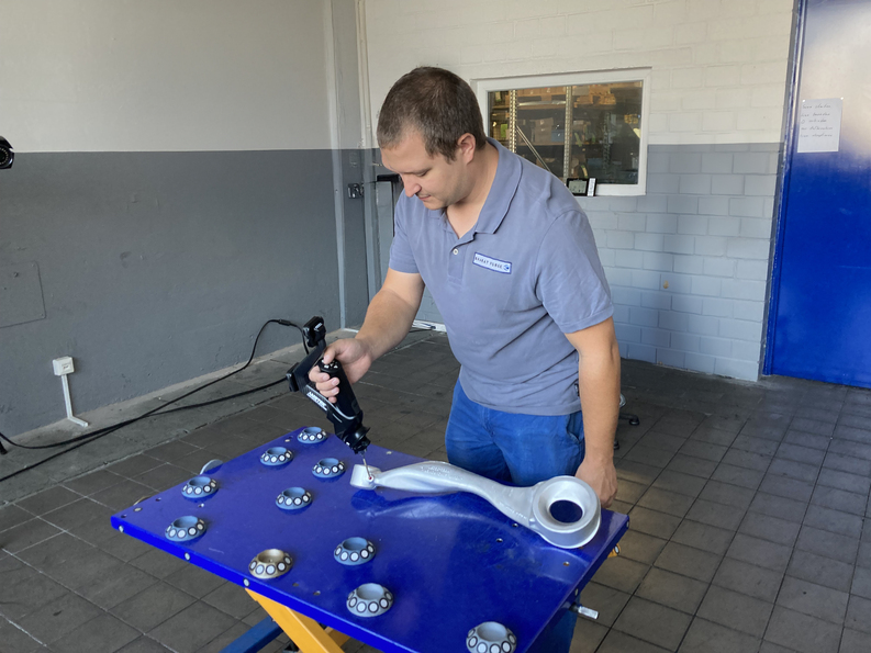 一名员工使用 HandyPROBE 便携式光学 CMM 采集金属元件的 3D 测量数据。