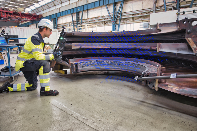 Dipendente con elmetto protettivo che usa uno scanner della serie HandySCAN 3D|MAX per misurare l'interno di una turbina molto grande.