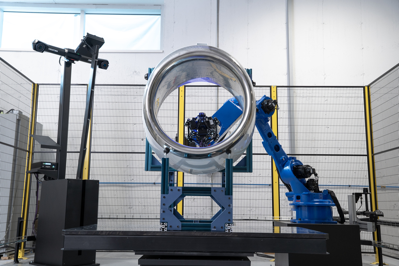 A large cylindrical part being measure by the robot-mounted MetraSCAN 3D-R inside the CUBE-R M4 measuring cell