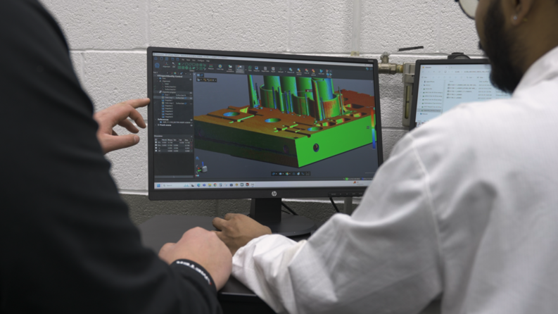 Especialistas en control de calidad mirando un mapa de colores mostrado con el software de inspección de Creaform en una pantalla de computadora