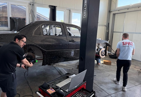 Two operators from AMB Aero work on acquiring the 3D measurements of a black vehicle