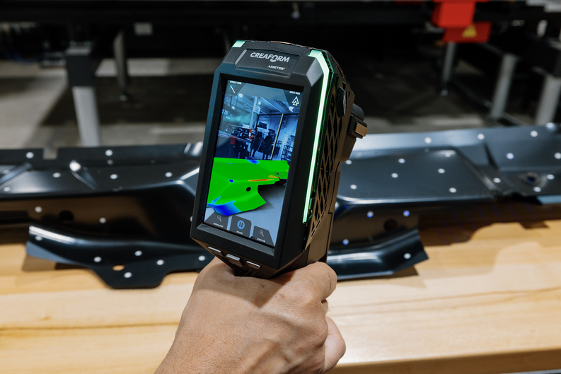 Close-up of the HandySCAN 3D|EVO Serie with its embedded screen displaying real-time mesh data during the inspection of a large, dark part