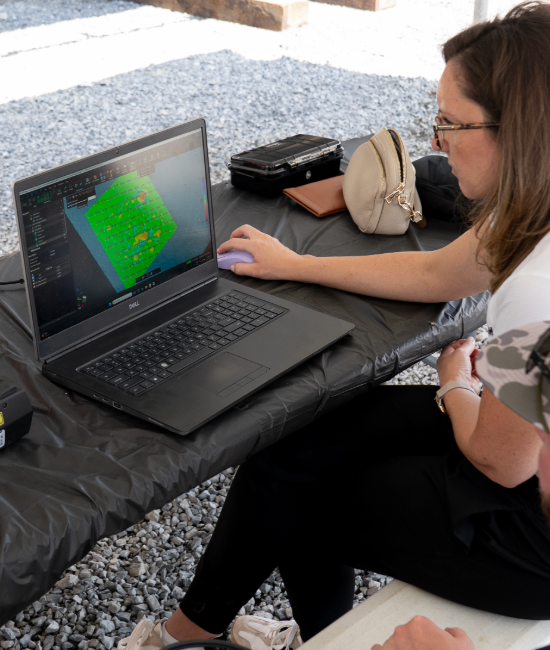 Laptop displaying 3D scanning software with a green model on the screen during outdoor inspection setup