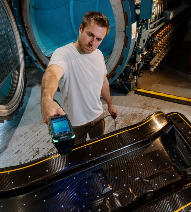 EVO Series 3D scanner inspecting a large black composite part in front of an autoclave