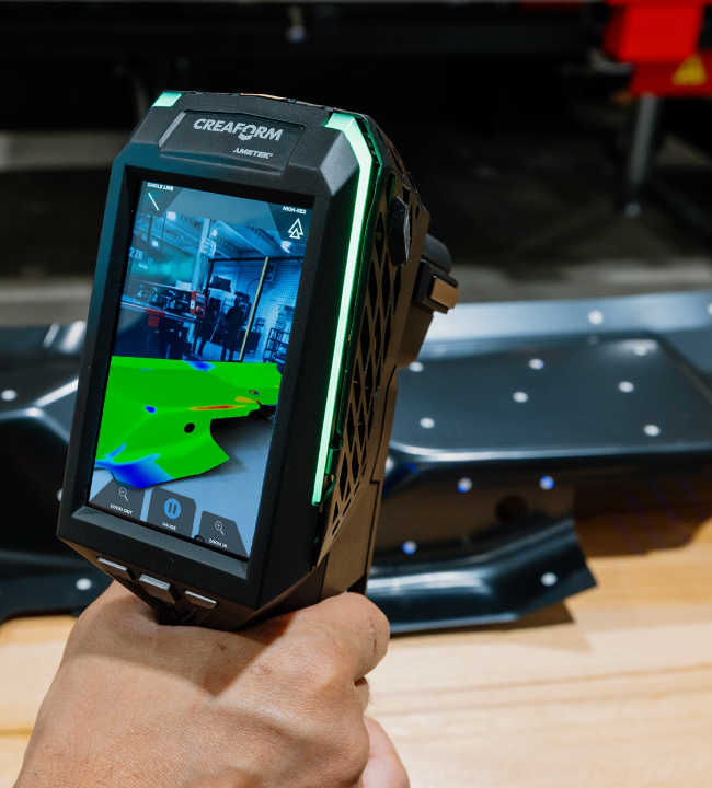 EVO Series 3D scanner scanning a sheet metal part, showing a color map pattern on the screen