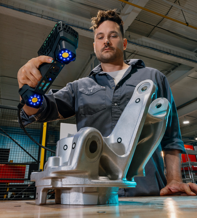 Person scanning a casting part with the EVO Series 3D scanner on a workbench