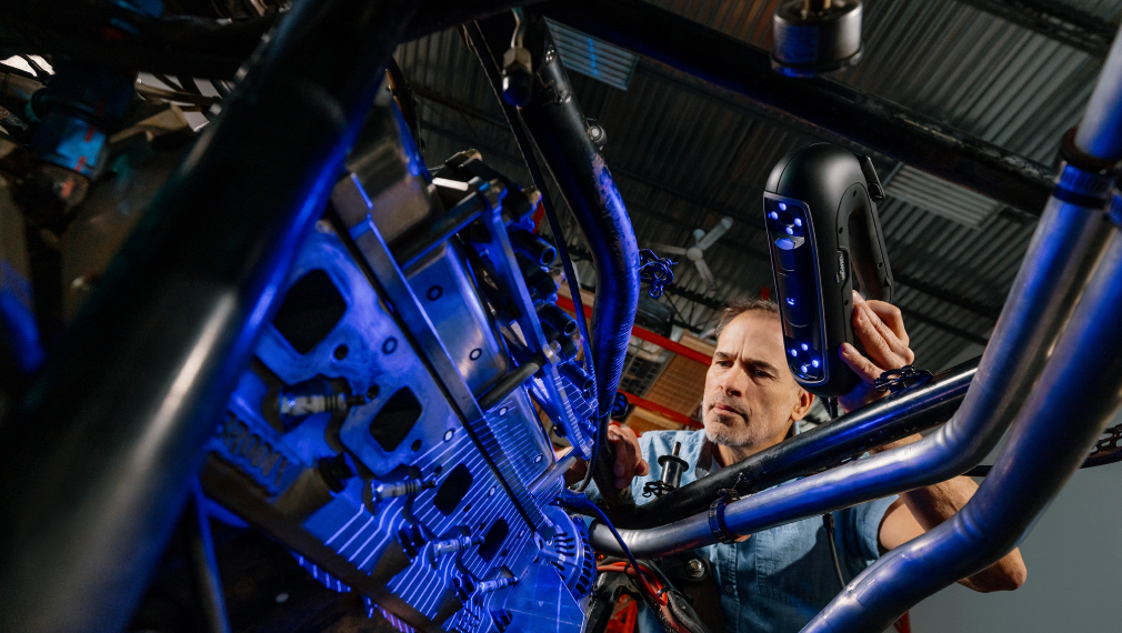 Expert using a PRO Series 3D scanner projecting blue laser lines while scanning a car frame