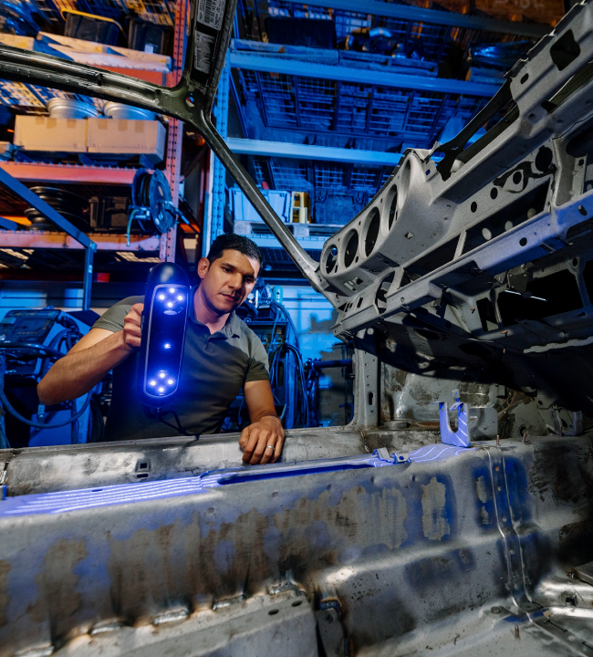 A technician scanning the interior of a car frame in an industrial workshop