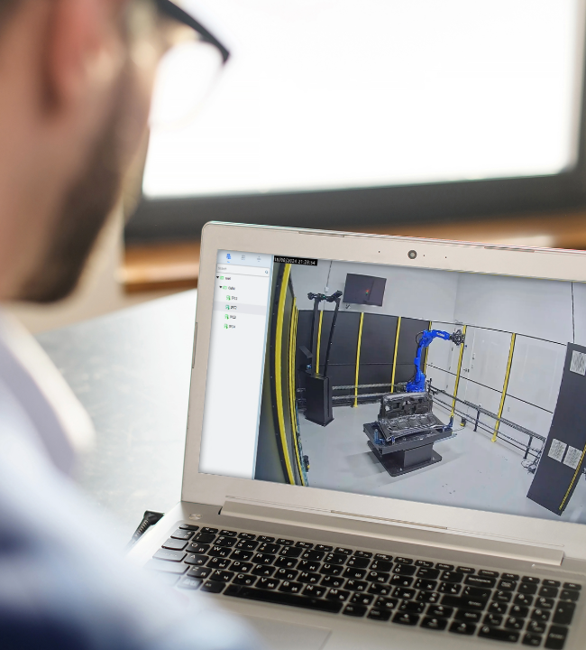 Person viewing four camera feeds of an automated measuring cell on a laptop screen
