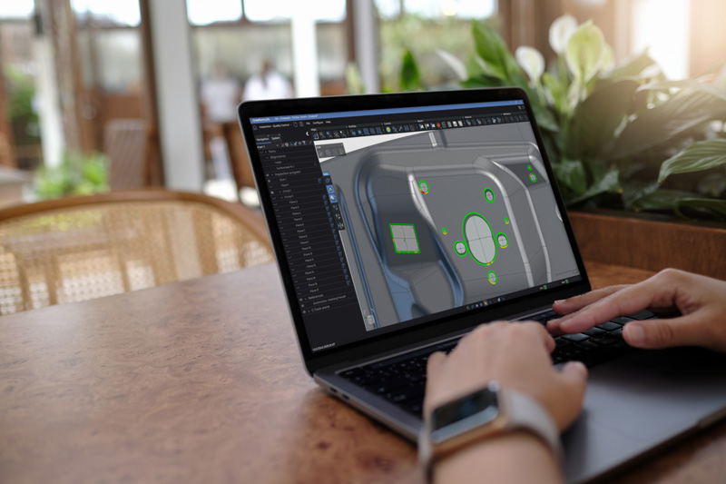 ノートパソコンを使ってテーブルに座り、Creaform Metrology SuiteのInspectionモジュールで部品を表示する人。