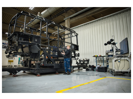 HOLON engineer performing 3D measurements on a full-scale vehicle frame structure in a production workshop using a MetraSCAN 3D with C-Track.