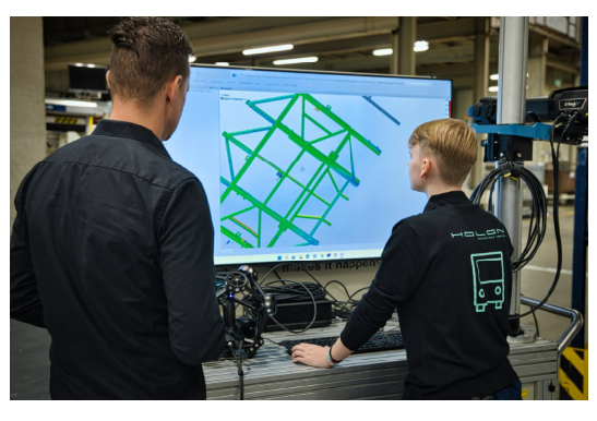 HOLON engineer and Creaform technician reviewing 3D measurement data of a vehicle frame with the PolyWorks software ecosystem during an inspection workflow on the shop floor.