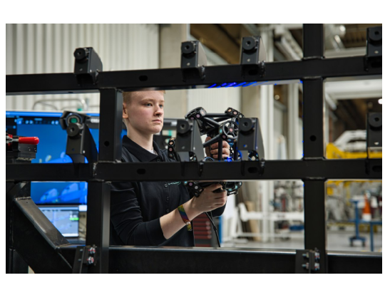 Técnico da HOLON utilizando um MetraSCAN 3D portátil para capturar dados 3D de uma estrutura de chassi durante a inspeção de peças de grande porte.
